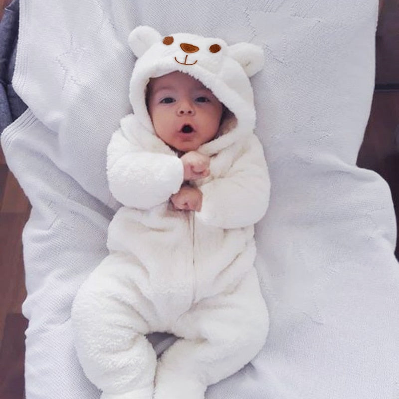 Baby in a white bear onesie sitting on a person's lap.